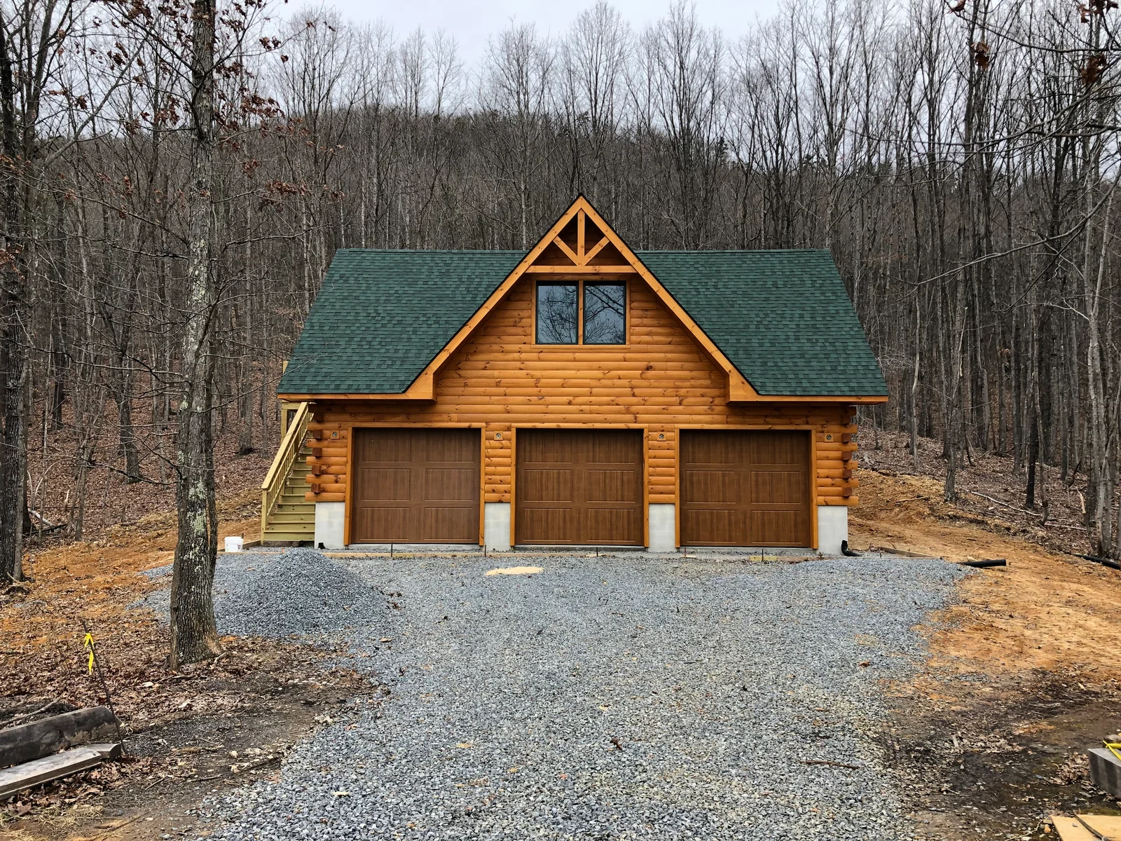 Timber garage with three doors and a centered roof gable
